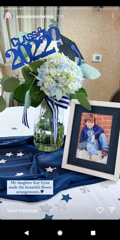 a vase filled with white flowers next to a blue and white table cloth on top of a table