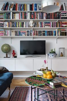 a living room with bookshelves and a television on the wall in front of it