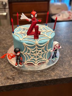 a birthday cake with spiderman figures on it and the number four in the middle