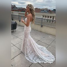 a woman in a white wedding dress standing on a balcony talking on her cell phone