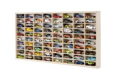 a bookcase filled with lots of toy cars on top of each other in front of a white wall