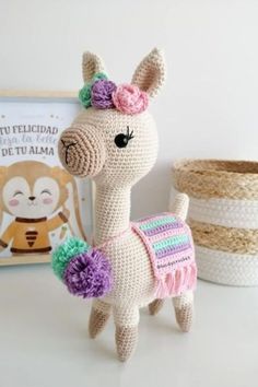 a crocheted llama is standing next to a basket