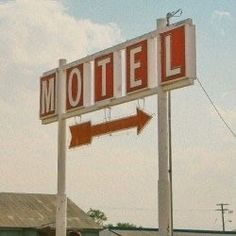 a red and white motel sign with an arrow pointing to the right on a pole