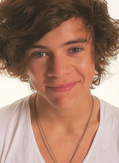 a close up of a person wearing a white shirt and necklace with a heart on it