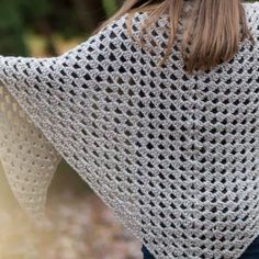 a woman wearing a white crocheted shawl with black dots on the back