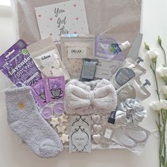 a gift basket filled with personal care items and baby's breathy socks next to flowers