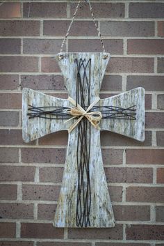 a wooden cross hanging on a brick wall