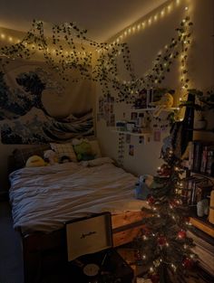 a bed room with a neatly made bed next to a christmas tree and lights hanging from the ceiling