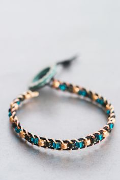 a close up of a bracelet on a white surface with a blue and gold bead