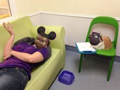 a person laying on a green couch next to a chair with mickey mouse face painted on it