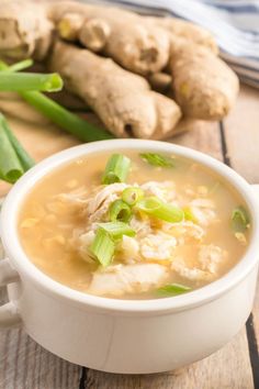 a white bowl filled with soup next to green onions