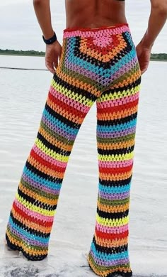 a woman wearing colorful crocheted pants standing in the snow with her hands on her hips