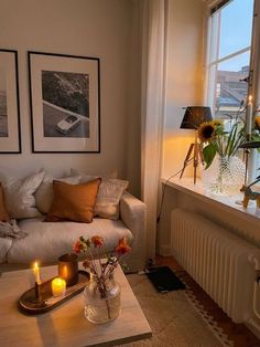 a living room filled with furniture and flowers on top of a table next to a window