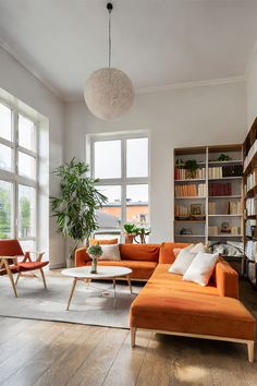 a living room filled with lots of furniture and bookshelves next to large windows