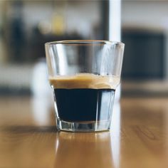 a glass filled with liquid sitting on top of a wooden table