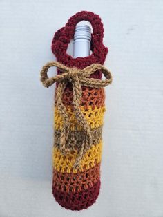 a crocheted wine bottle cover with a rope tied around it