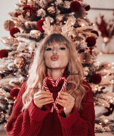 a woman holding a candy cane in front of a christmas tree