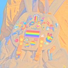 a child's back pack with patches and rainbow stickers on the front pocket