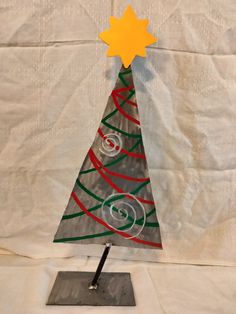 a small metal christmas tree on top of a white cloth covered tablecloth with an orange star above it