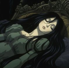 a woman laying on top of a bed in a green dress with long black hair