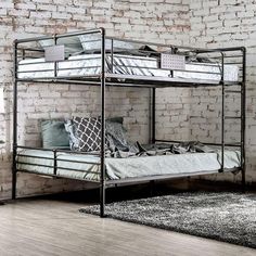 a metal bunk bed sitting on top of a wooden floor next to a brick wall