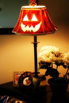 a lamp with a jack - o'- lantern on it next to some flowers