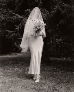 black and white photograph of a woman in a wedding dress holding a bridal bouquet