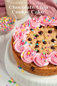 a cookie cake with pink frosting and sprinkles on a white plate