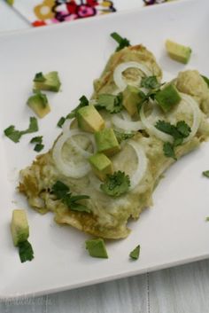 a white plate topped with an omelet covered in onions and cilantro