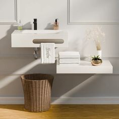 a bathroom with white walls and wooden flooring next to a basket filled with towels