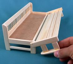 a hand holding a miniature wooden bed frame