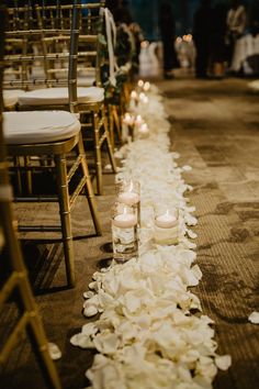 the aisle is lined with white flowers and candles