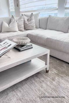 a white coffee table sitting in front of a couch with pillows on top of it