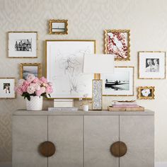 a dresser with flowers and pictures on the wall