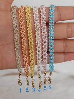 four different colored bracelets with gold chains and beads on each strand, all in different colors