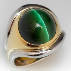 This handsome ring features a central band of eighteen karat yellow gold, bezel set with an oval cabochon cut, natural cat's-eye tourmaline. Two (2) platinum accent bands are attached to the outer edges of the gold band. The ring measures 20.1mm at the top, rises 10.2mm above the finger, tapering to 9.6mm wide and 1.6mm thick at the base of the European style shank. This ring is currently a size 9. Modern Formal Gemstones With Polished Finish, Oval Cabochon Fine Jewelry With Polished Finish, Polished Oval Cabochon Fine Jewelry, Modern Cabochon Emerald Ring For Formal Occasions, Modern Formal Emerald Cabochon Ring, Modern Oval Gemstones With Polished Finish, Modern Yellow Gold Emerald Cabochon Ring, Modern Round Cabochon Emerald Ring, Modern Cabochon Emerald Ring