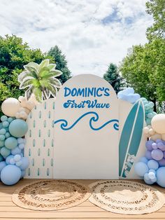 a surfboard sign surrounded by balloons and other decorations