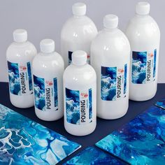 six bottles of liquid sitting on top of a table next to blue and white artwork