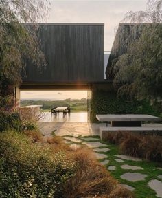 the house is surrounded by greenery and has a stone path leading to it that leads to an outdoor dining area