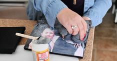 a person is holding a brush near a photo on a table