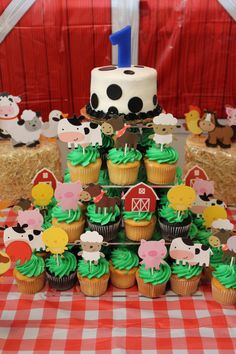 a table topped with cupcakes covered in green frosting and farm animals on top of them