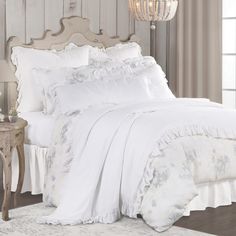 a white bed with ruffled bedspread and pillows