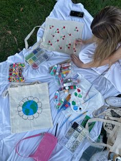 a woman laying on the ground next to bags and other crafting supplies in front of her