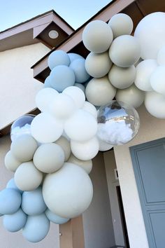 some white and blue balloons hanging from the side of a house