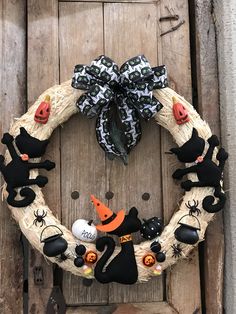 a halloween wreath with black cats, pumpkins and other decorations hanging on a door