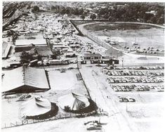 an old black and white photo of cars parked in a parking lot with tents on the ground