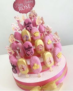 a pink and gold birthday cake with lots of candies on it's top