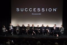 a group of people sitting on top of a stage in front of a large screen