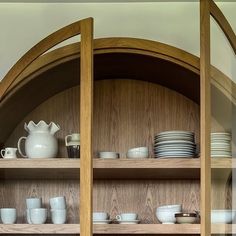 a wooden shelf filled with dishes and cups