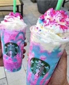 two starbucks drinks with sprinkles on them are being held by someone's hand